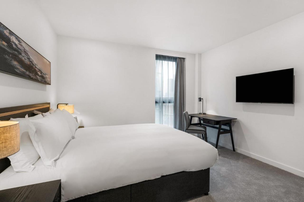Citysuites 2 Aparthotel Salford  Exterior foto The photo shows a modern hotel room featuring a large bed with white linens and a dark headboard. There are two bedside lamps on either side of the bed. A desk with a chair is placed against one wall, and a flat-screen TV is mounted on another wall. 