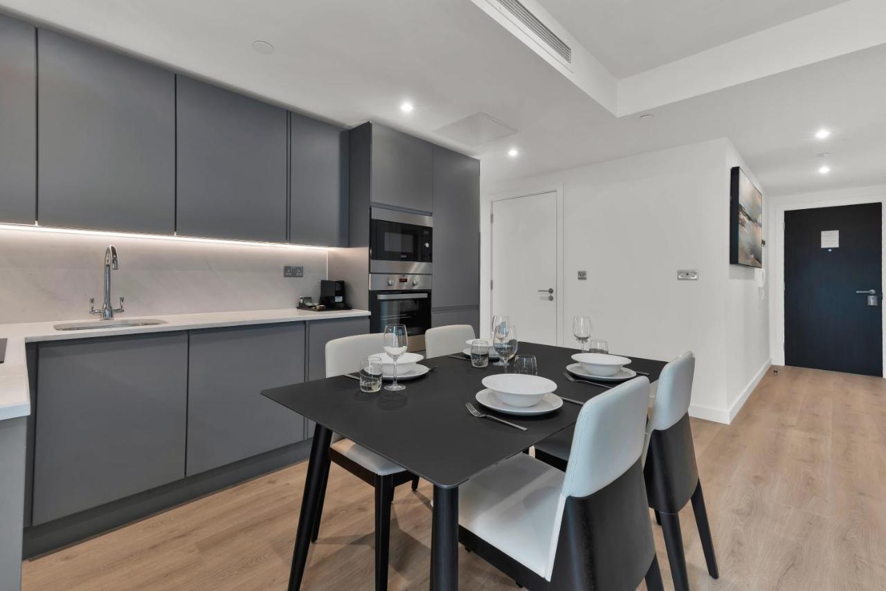Citysuites 2 Aparthotel Salford  Exterior foto The photo shows a modern kitchen and dining area. There are sleek gray cabinetry and countertops, with a built-in oven and microwave. The kitchen is well-lit, featuring under-cabinet lighting that adds to the contemporary feel. In the dining area, th