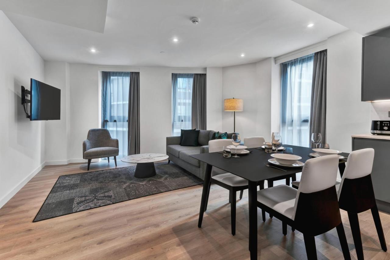 Citysuites 2 Aparthotel Salford  Exterior foto The photo shows a modern living space that includes a living area and dining area. 

- **Living Area**: There's a gray sofa with a coffee table in front of it, along with a single armchair. A large flat-screen TV is mounted on the wall. The space is 