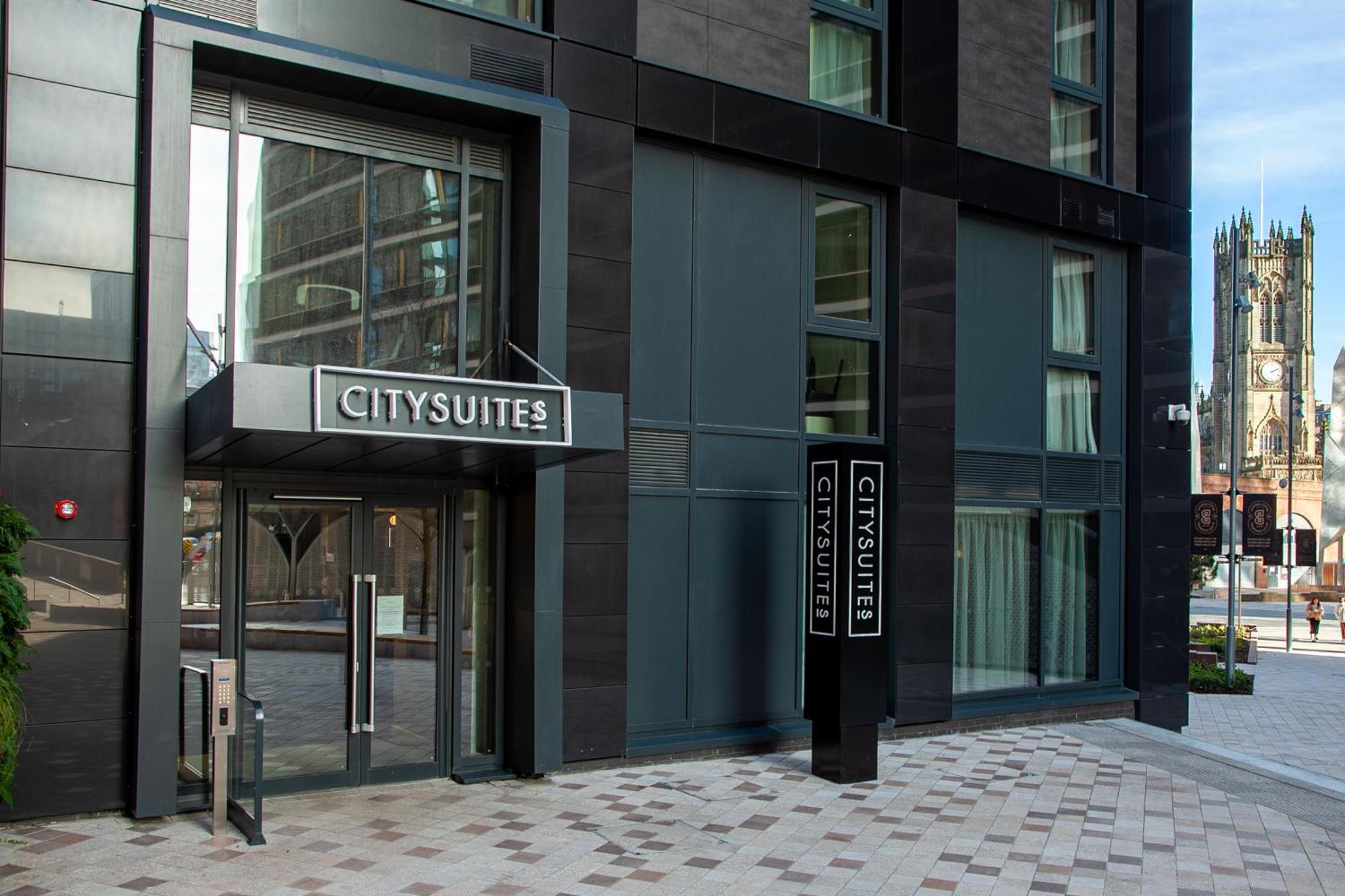 Citysuites 2 Aparthotel Salford  Exterior foto The photo shows the entrance to a modern building labeled "CITYSUITES." The entrance features large glass doors and a sleek, contemporary design. The building has dark exterior panels and large windows, suggesting a stylish and urban environment. The